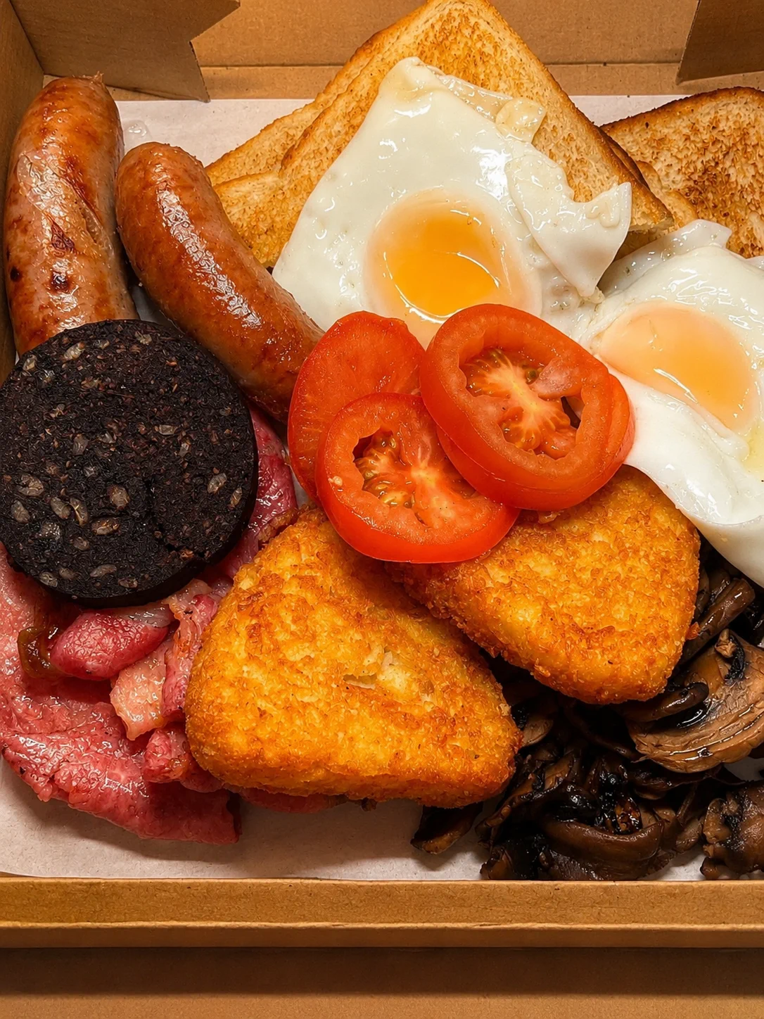 A breakfast box with eggs, sausages and hash browns