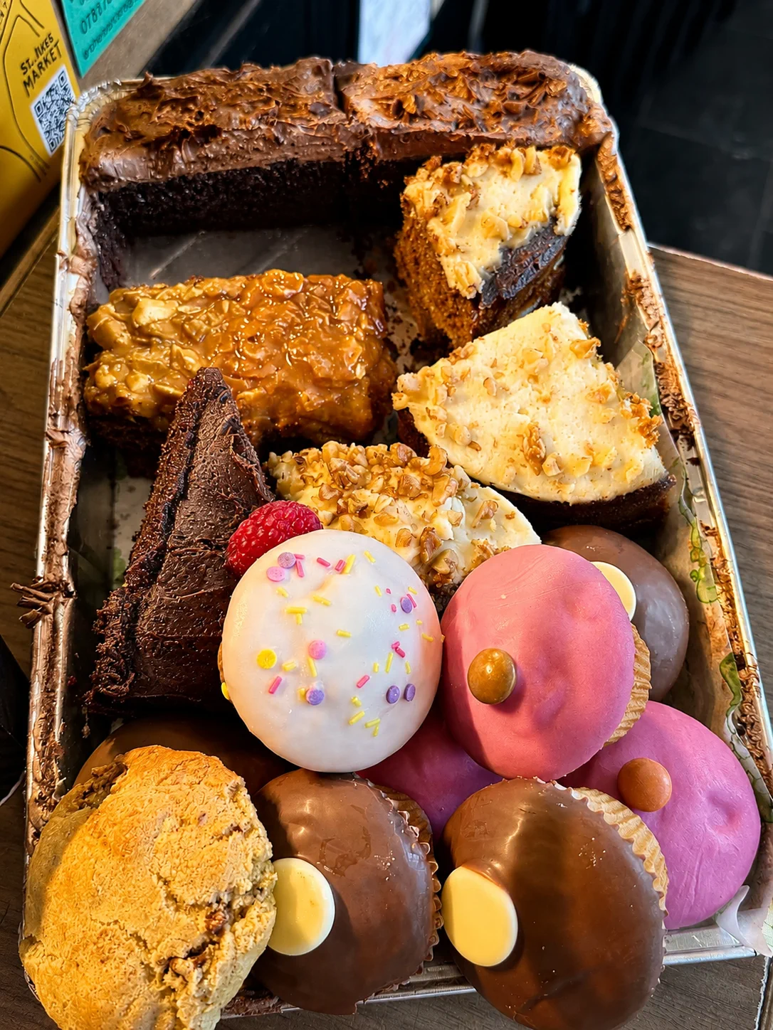 A tray of cakes and colourful doughnuts